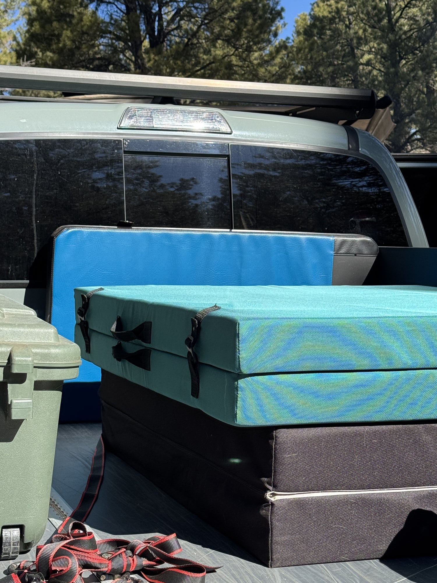 Blue surfboard leaning against a vehicle with trees in the background